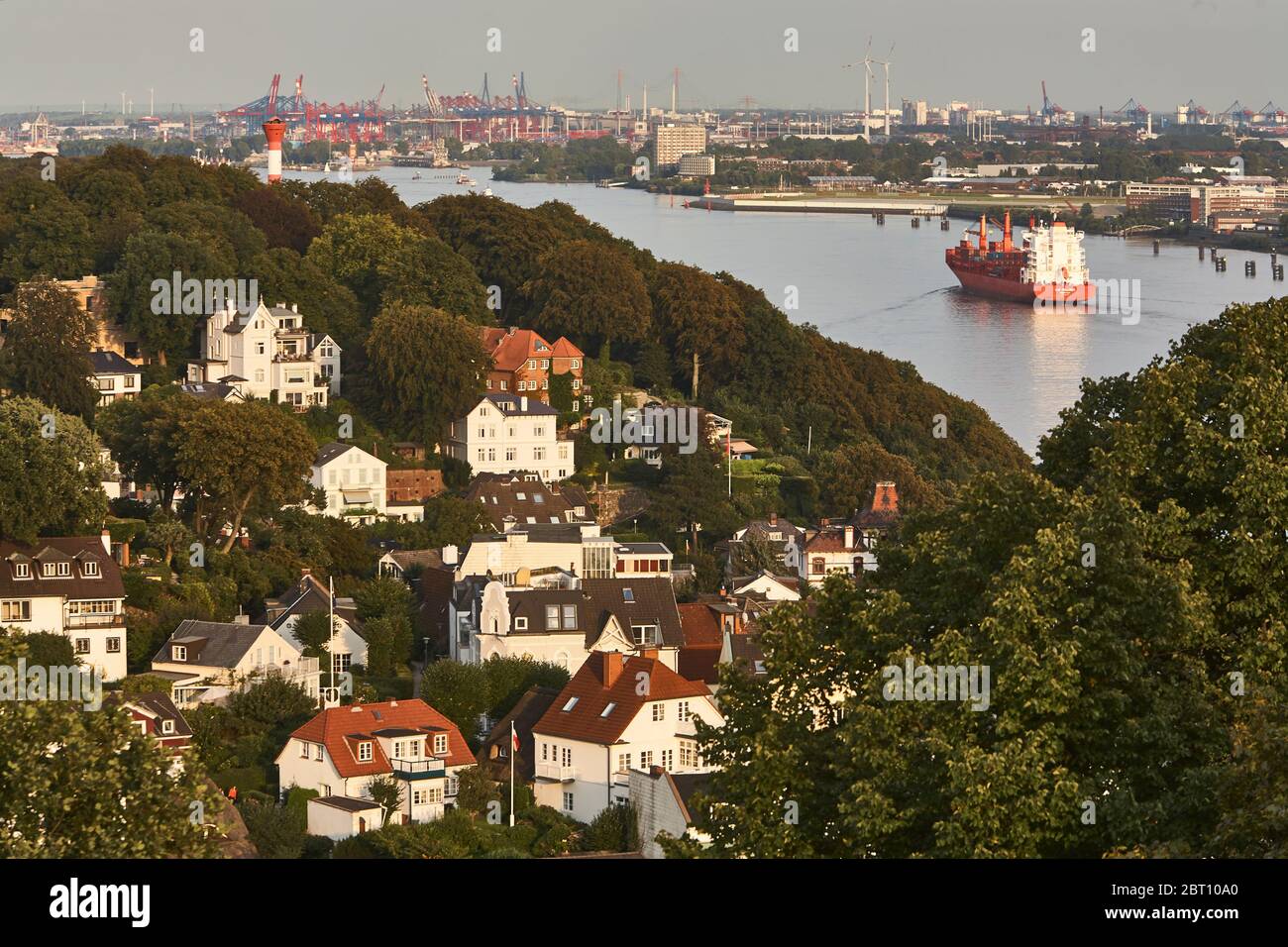 Ein Containerschiff kommt die Elbe flussaufwärts Richtung Hamburger Hafen. Im Vordergrund Häuser des Hamburger Stadtviertels Blankenese. Stockfoto