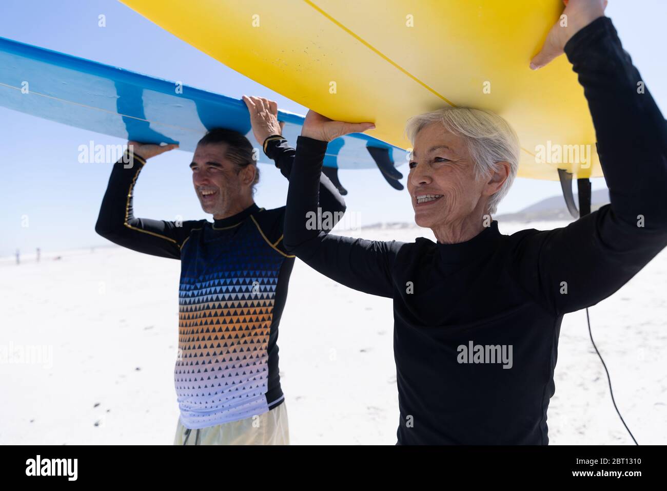 Ältere kaukasische Paar hält Surfbretter am Strand. Stockfoto