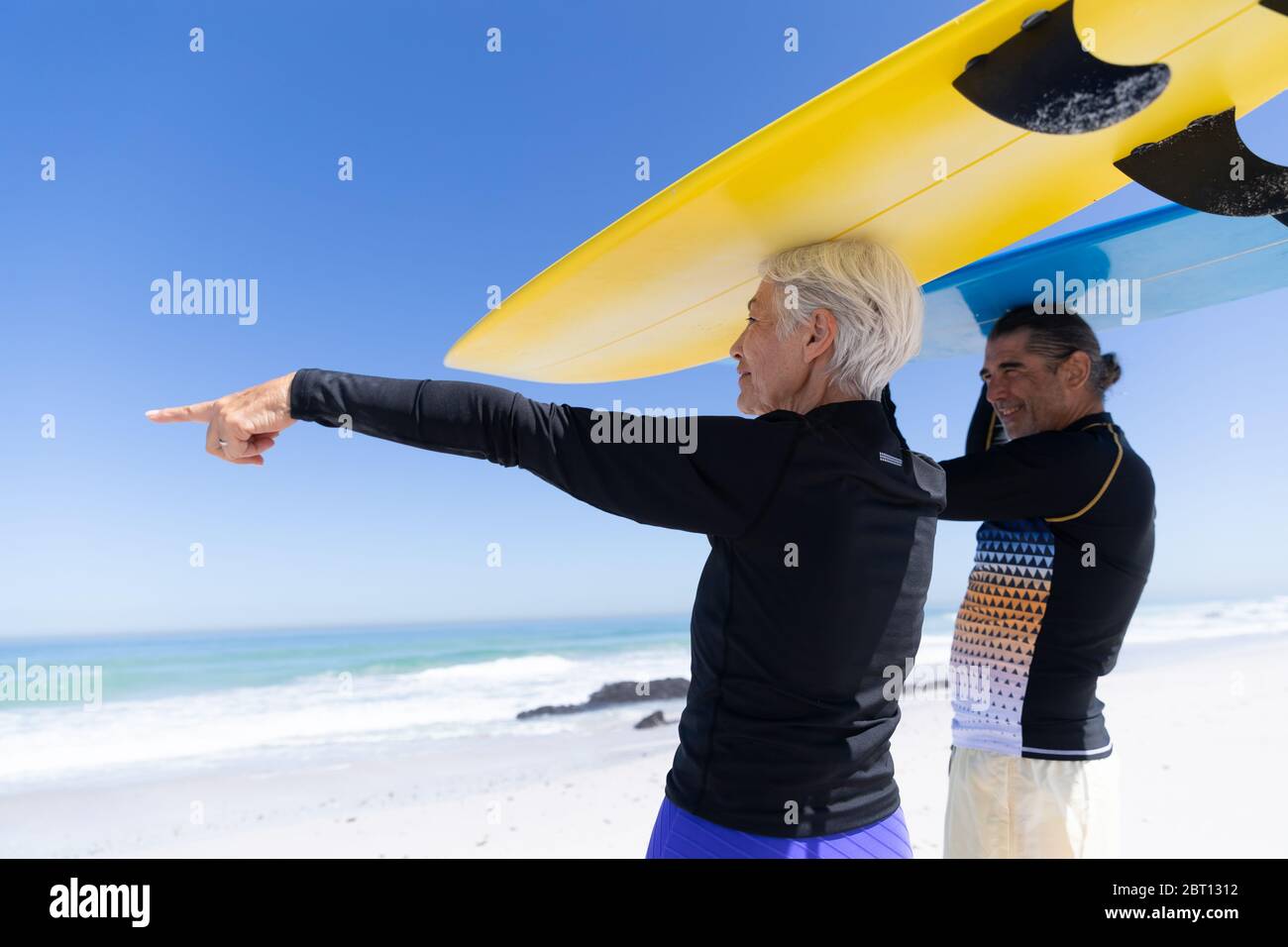 Ältere kaukasische Paar hält Surfbretter am Strand. Stockfoto