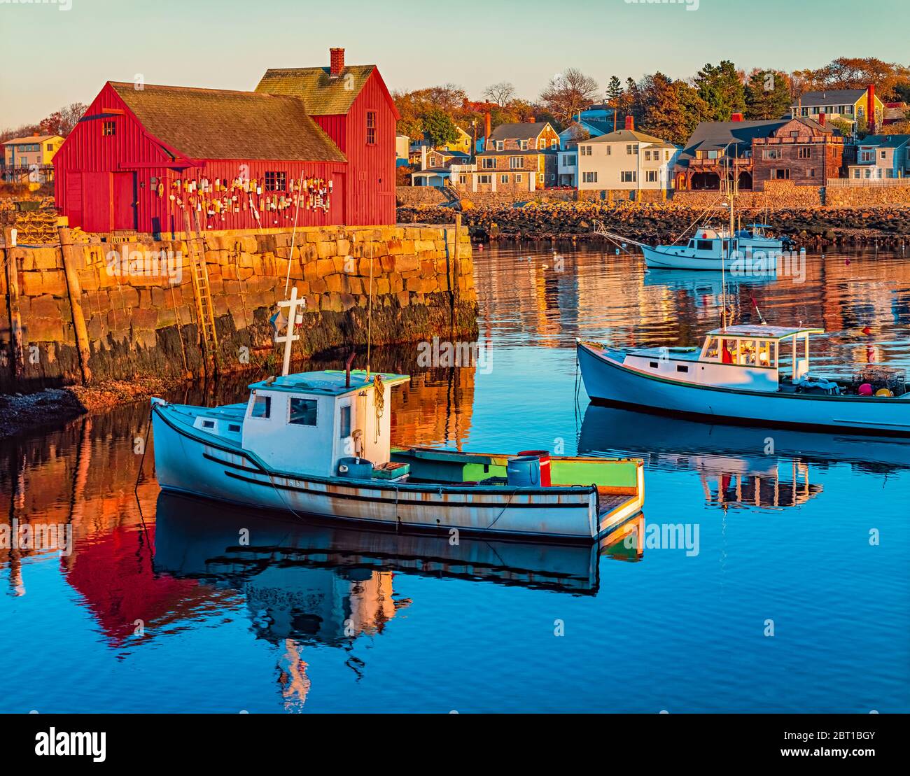 Rockport Harbour in Massachusetts mit seinen Hummerbooten und seinem Dorf spiegelt sich im stillen Wasser des Tages wider. Die Farben verleihen der Stadt ein nostalgisches Gefühl Stockfoto