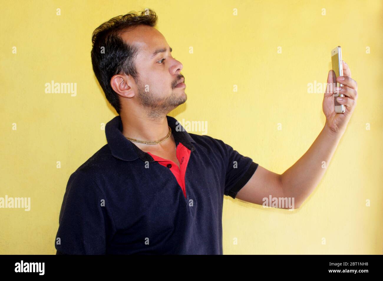 Junge schöne indische Mann unter Selfie mit Handy auf gelbem Hintergrund Stockfoto