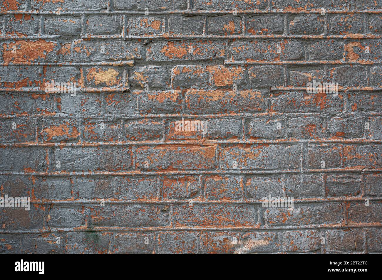 Hintergrund der alten, schmutzigen orangefarbenen Ziegelwand mit abblätternder Silberfarbe. Wandstruktur. Alte, rissige Farbe an der Wand. Hintergrund der Vorlage Stockfoto