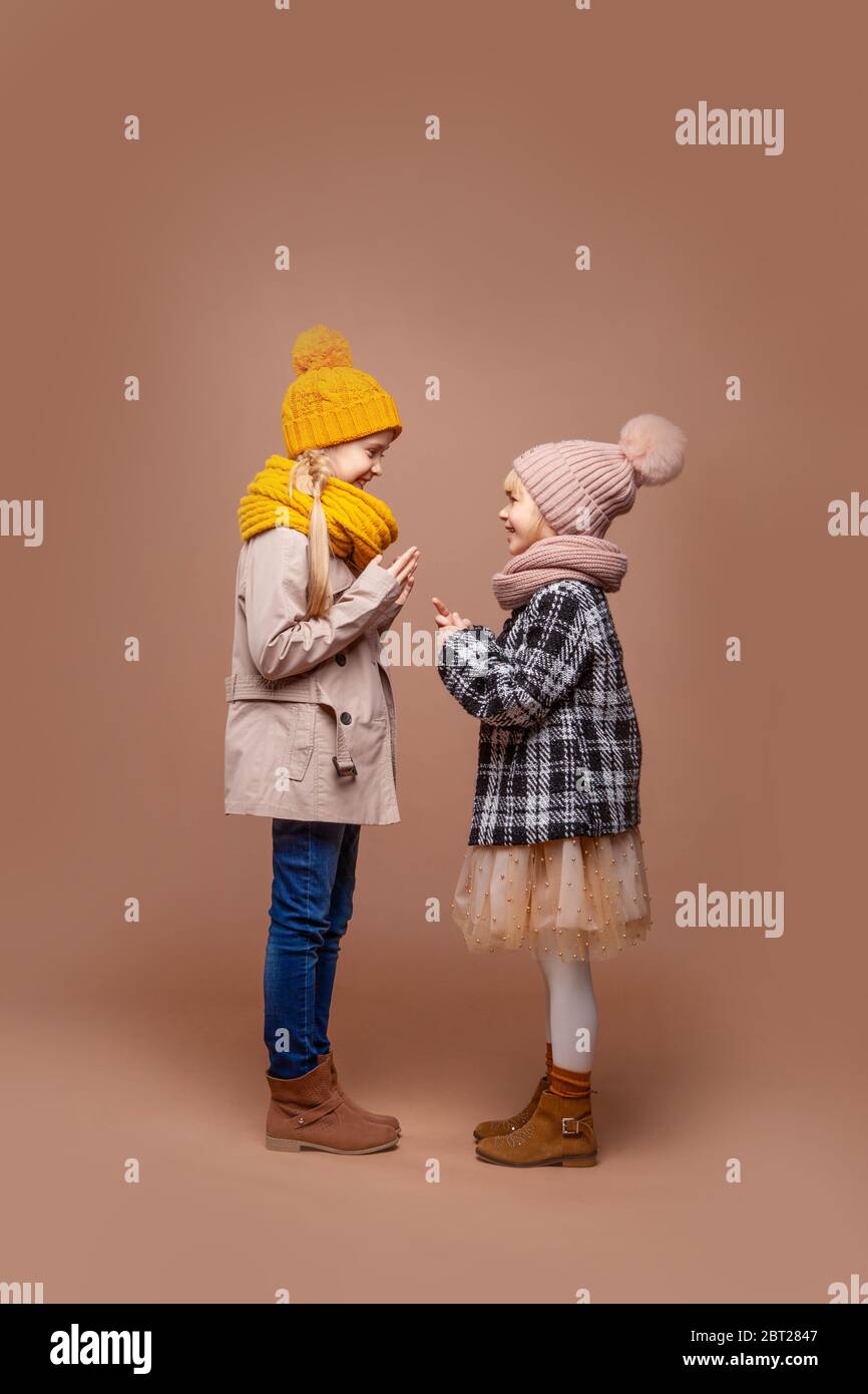 Zwei süße Mädchen in Herbst Straßenkleidung reden, lachen und gestikulieren gekleidet Stockfoto