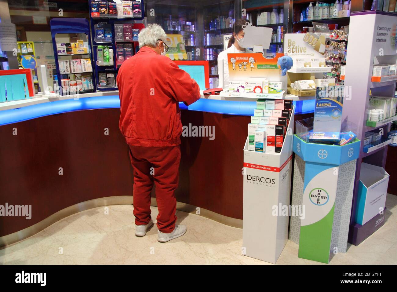 Ein Kunde in einer Apotheke während Phase 2 des Notfalls von covid-19 kauft Medikamente. Der Zähler ist mit Paneelen isoliert, um Kunden zu distanzieren Stockfoto