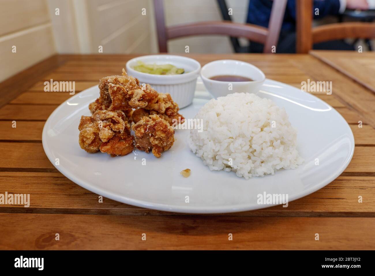 Im japanischen Restaurant werden auf einem Holztisch heimelige Gerichte wie Karaage oder japanisches gebratenes Huhn serviert, mit Misosuppe, Salat und gedünstetem Reis. Stockfoto