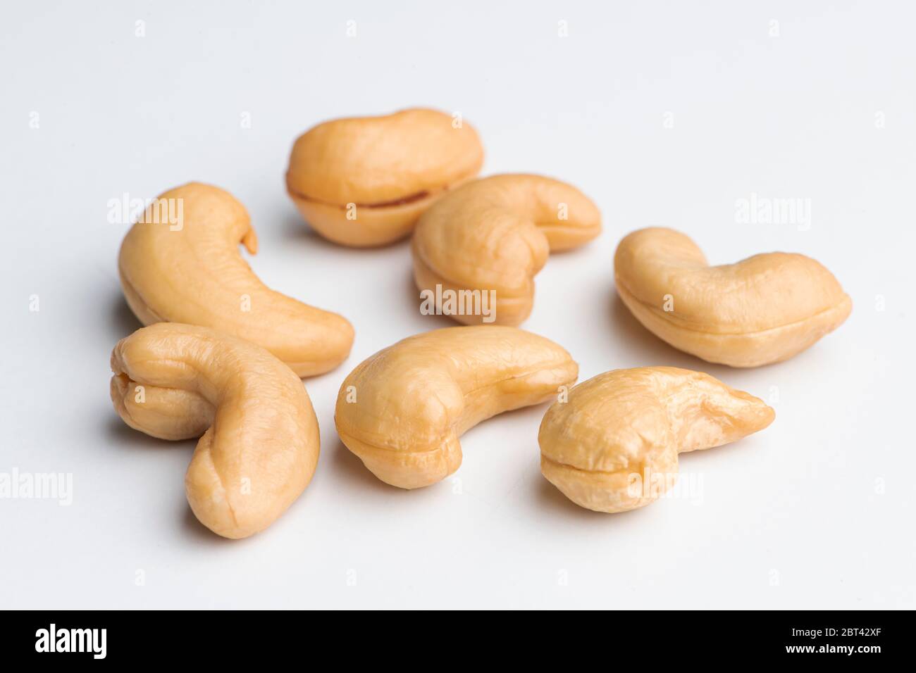 Viele frische Cashews auf verschiedenen Positionen auf weißem Hintergrund Stockfoto