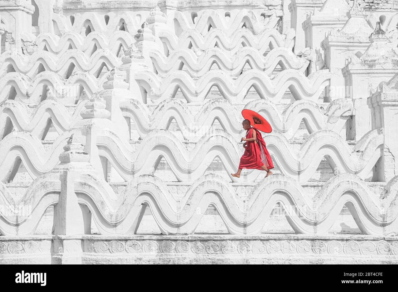 Novize Mönch mit einem Sonnenschirm über eine Tempelmauer, Myanmar Stockfoto
