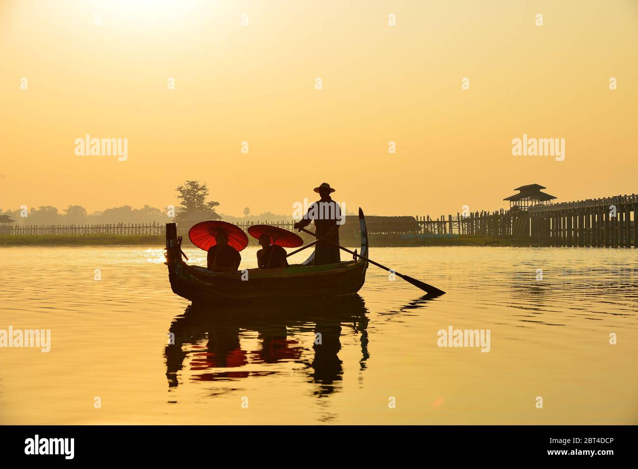 Mann und zwei Novizen segeln bei Sonnenaufgang in der Nähe der U Bein Brücke, Mandalay, Myanmar Stockfoto
