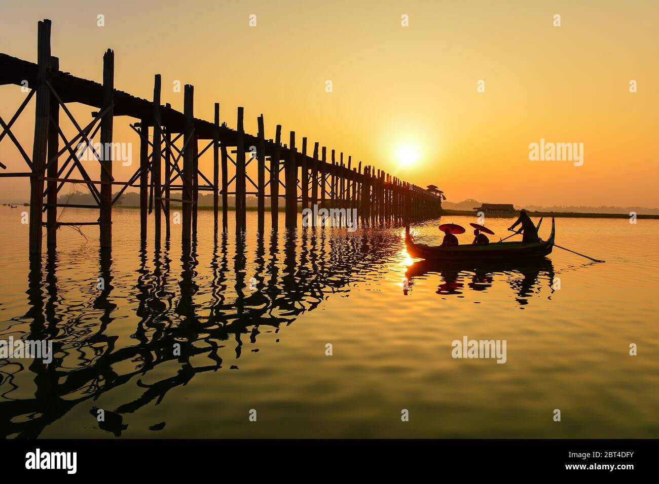 Mann und zwei Novizen segeln bei Sonnenaufgang in der Nähe der U Bein Brücke, Mandalay, Myanmar Stockfoto