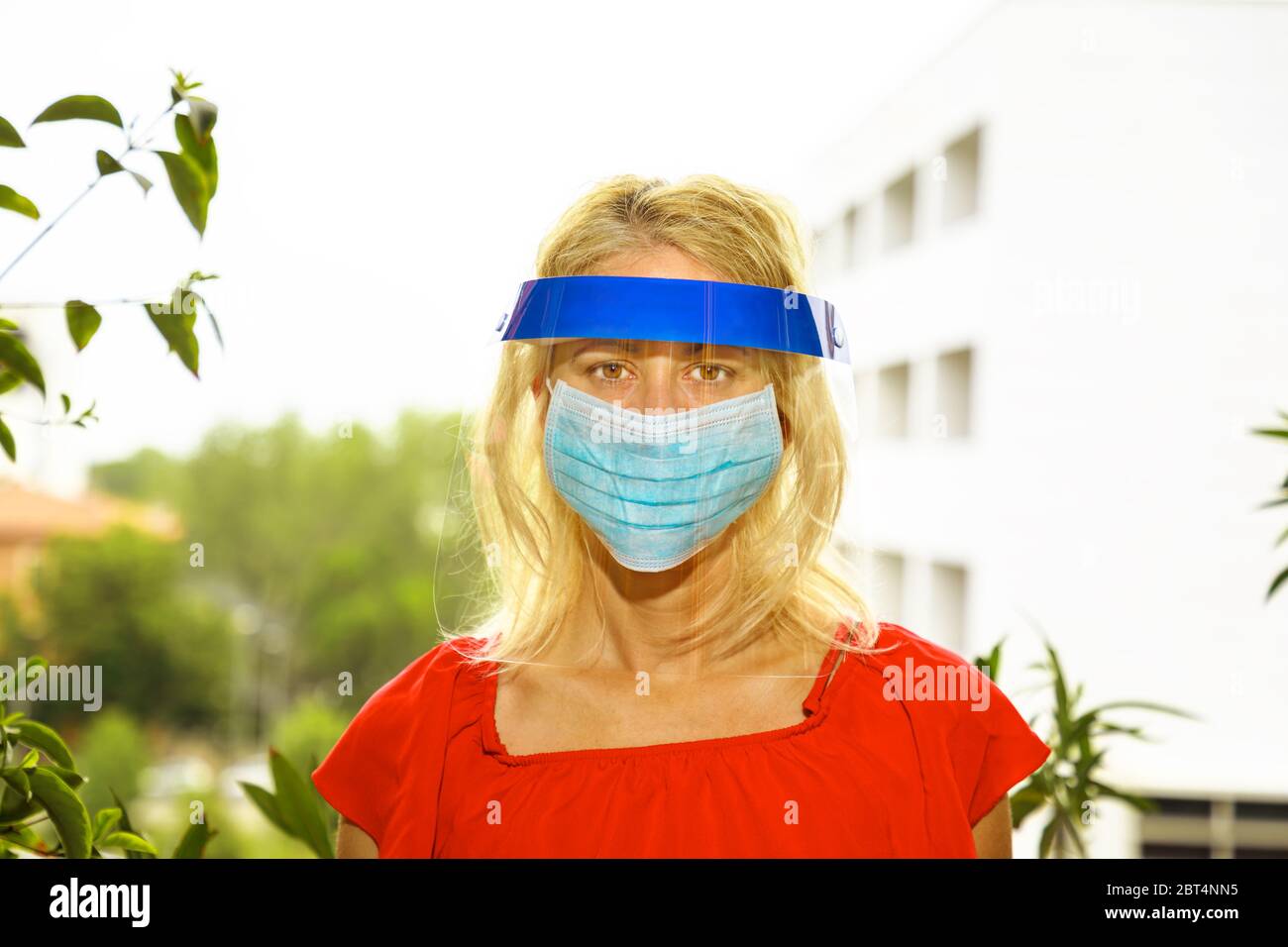 Frau mit chirurgischer Maske und Schutzvisier im Gesicht, isoliert auf weißem Stadthintergrund. Konzept des COVID-19 Epidemie Ausbruch, Quarantäne für Stockfoto