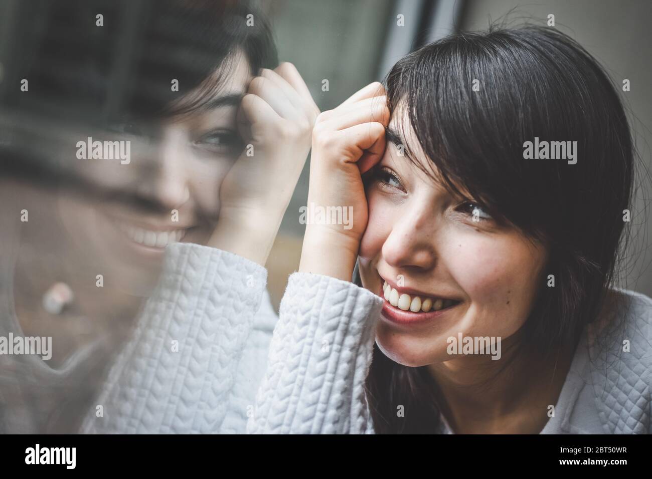 Porträt einer Frau, die aus einem Fenster schaut Stockfoto