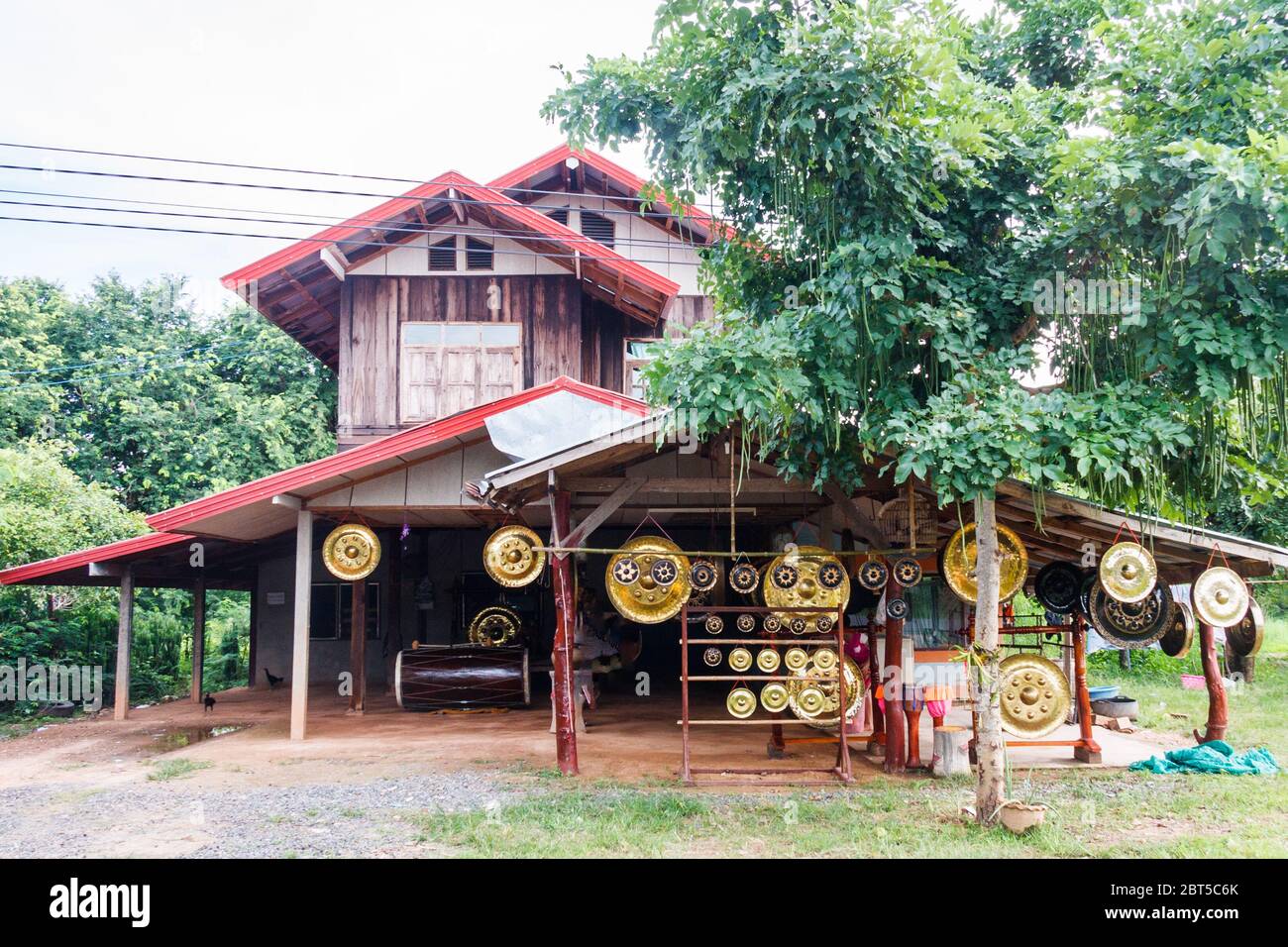 Gongs hängen vor einer Werkstatt und einem Laden in Ubon Ratchathani, Thailand Stockfoto