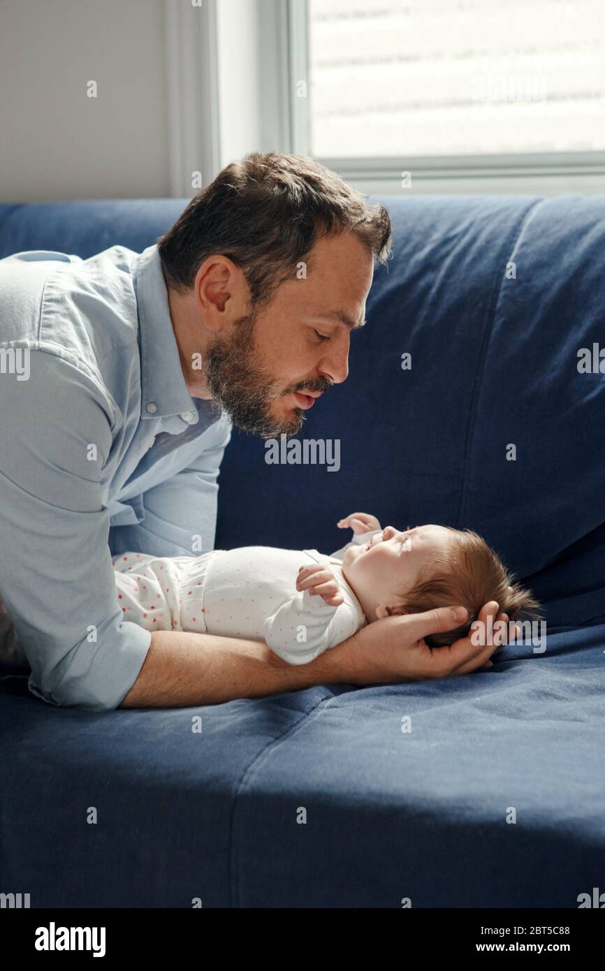 Stolzer kaukasischer Vater im Gespräch mit neugeborenen Mädchen. Lächelnd glücklich Eltern Mann beruhigend Tochter Sohn. Authentische Lifestyle Elternschaft Vaterschaft Stockfoto