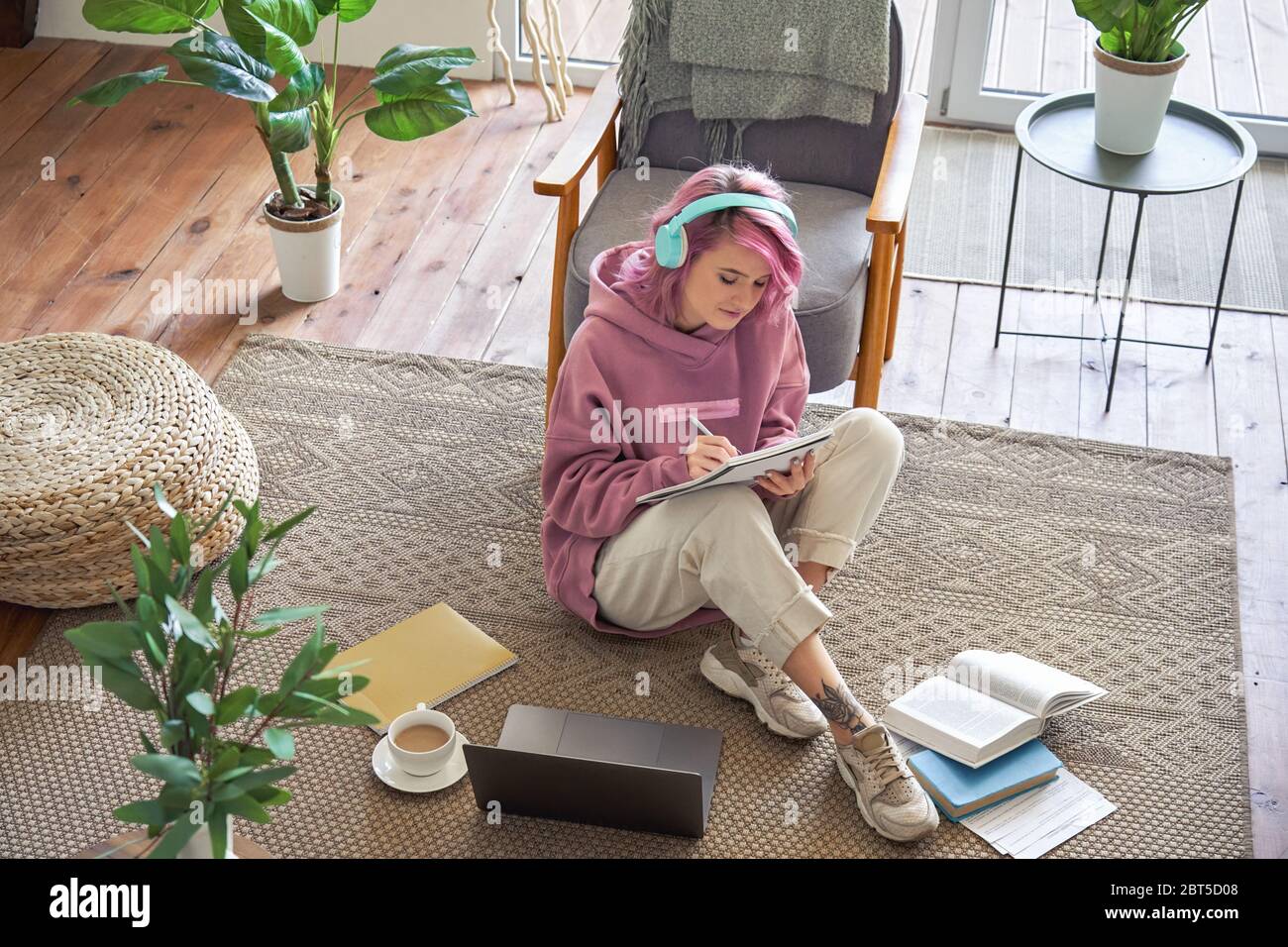 Teen Mädchen tragen Kopfhörer Videokonferenzen auf Laptop sitzen auf dem Boden, Draufsicht. Stockfoto