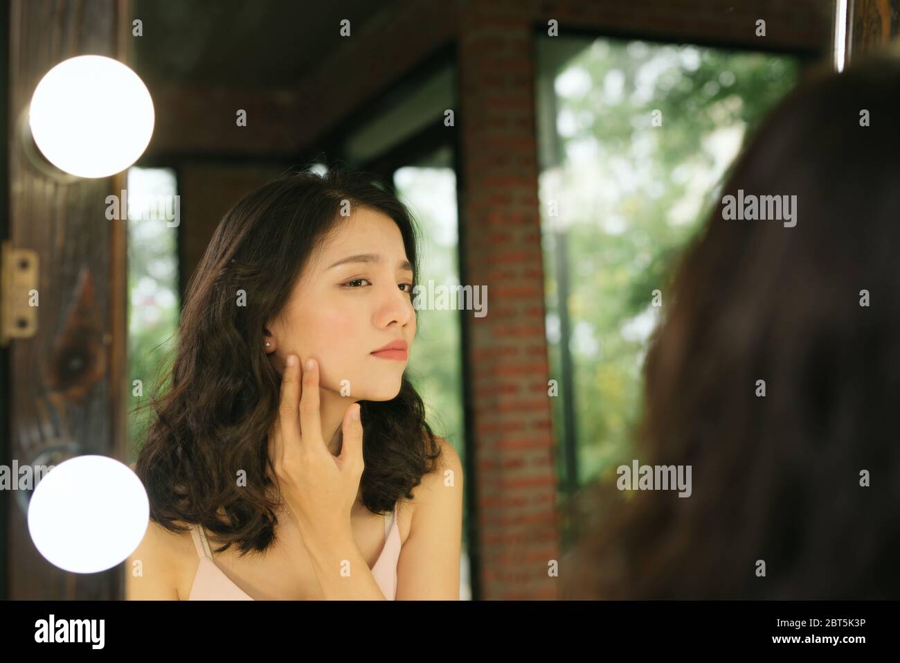 Reflexion im Spiegel. Frau schaut in den Spiegel, bemerken die ersten Fältchen Stockfoto