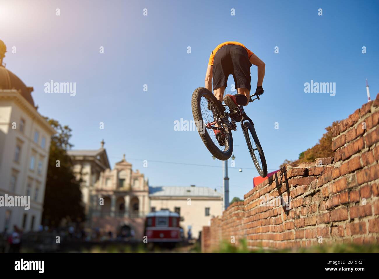 Rückansicht von Amateur-Radfahren durchführen Trick. Sportler im Stadtzentrum auf einem Hintergrund der Architektur üben Springen auf einem Mountainbike. Konzept des Sportlebens. Stockfoto