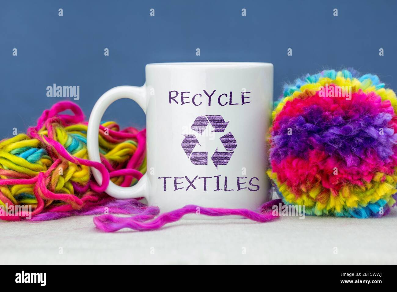 Selbstgemachtes Pom Pom aus recycelter Wolle, mit Becher. Recyceln Sie Textilien Text und Symbol auf Tasse. Nachhaltiges Wohnen zu Hause Konzept Stockfoto