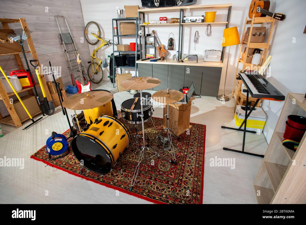 Interieur der zeitgenössischen Garage oder Studio von jungen Musiker mit Musikinstrumenten stehen auf Teppich, Werkzeuge und andere Dinge herum Stockfoto
