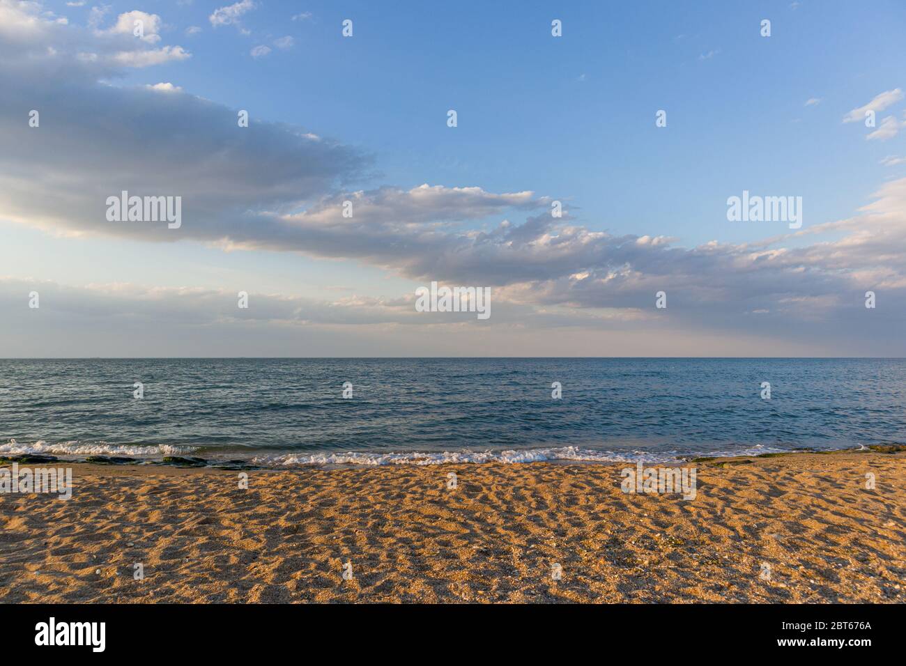 Glatte Linien von Sand, Meer und Himmel mit Wolken auf dem Hintergrund. Stockfoto