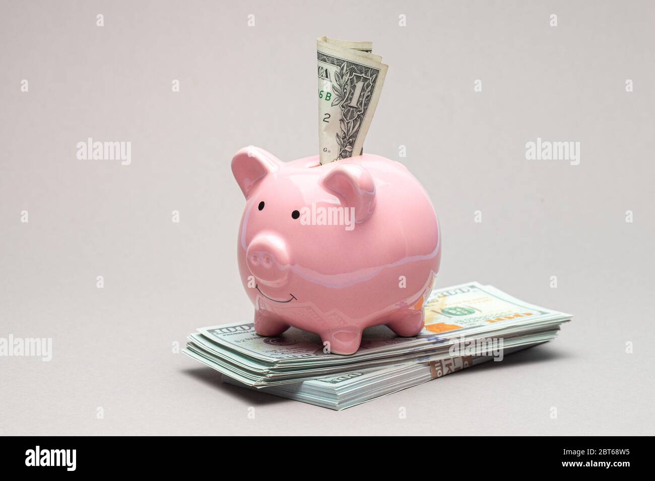 Rosa Sparschwein und Dollar-Rechnung auf einem grauen Hintergrund. Stockfoto
