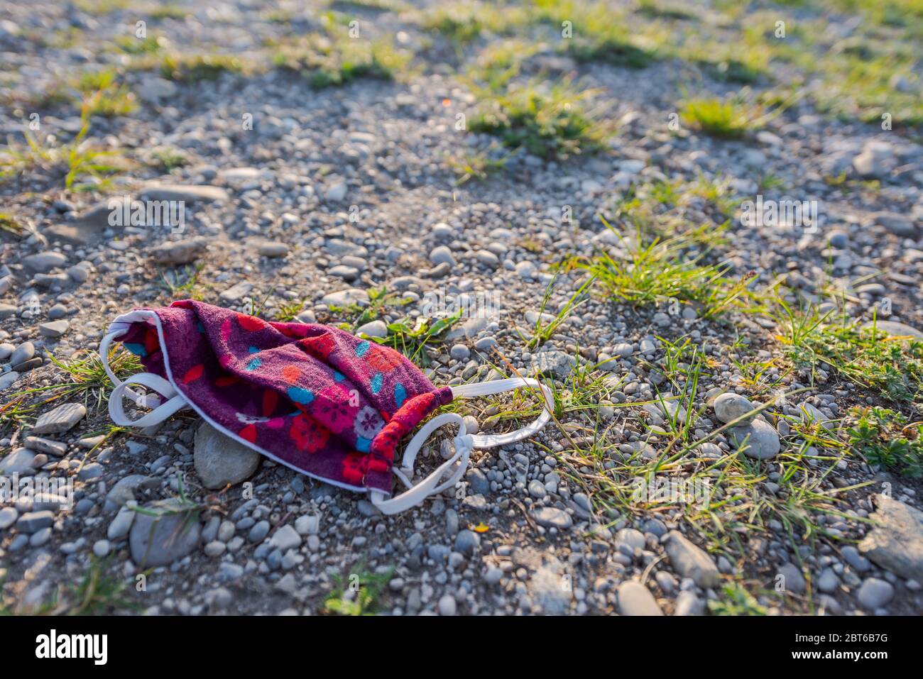 Entsorgt bunten Gesichtsschutz Maske auf Kiesstrand des lokalen Badesee während Corona Pandemie 2020 liegen Stockfoto