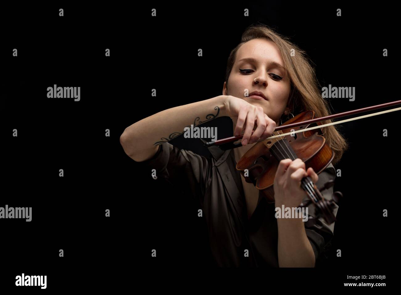 Leidenschaftliche professionelle Musikerin spielt auf einer klassischen antiken handgefertigten Holzbarocke Geige mit Fokus auf ihre Hand und Bogen über schwarz Stockfoto