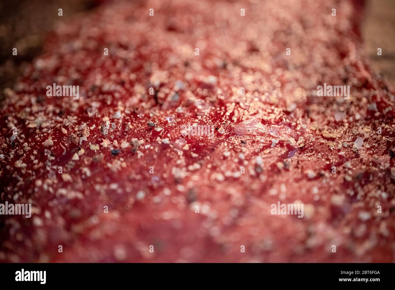 Pfeffer und Gewürze auf dem rohen Fleischsteak aus nächster Nähe mischen Stockfoto