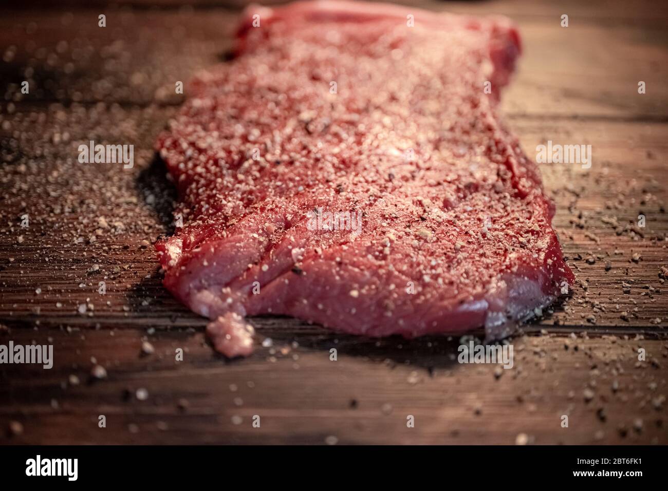 Pfeffer und Gewürze auf dem rohen Fleischsteak aus nächster Nähe mischen Stockfoto