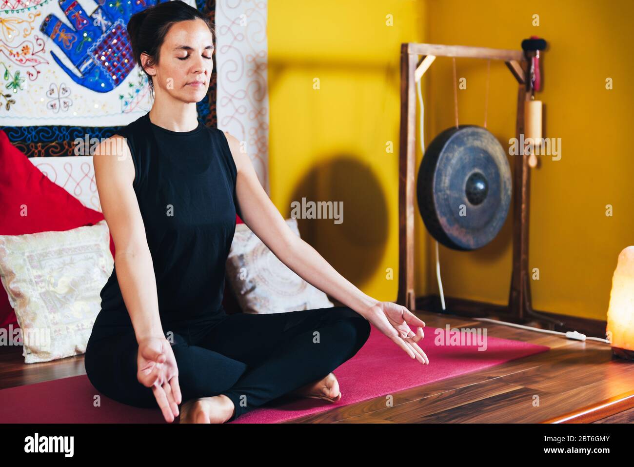 Junge Frau, die Yoga in der Meditationsposition von Sukhasana macht. Konzept der Entspannung Stockfoto