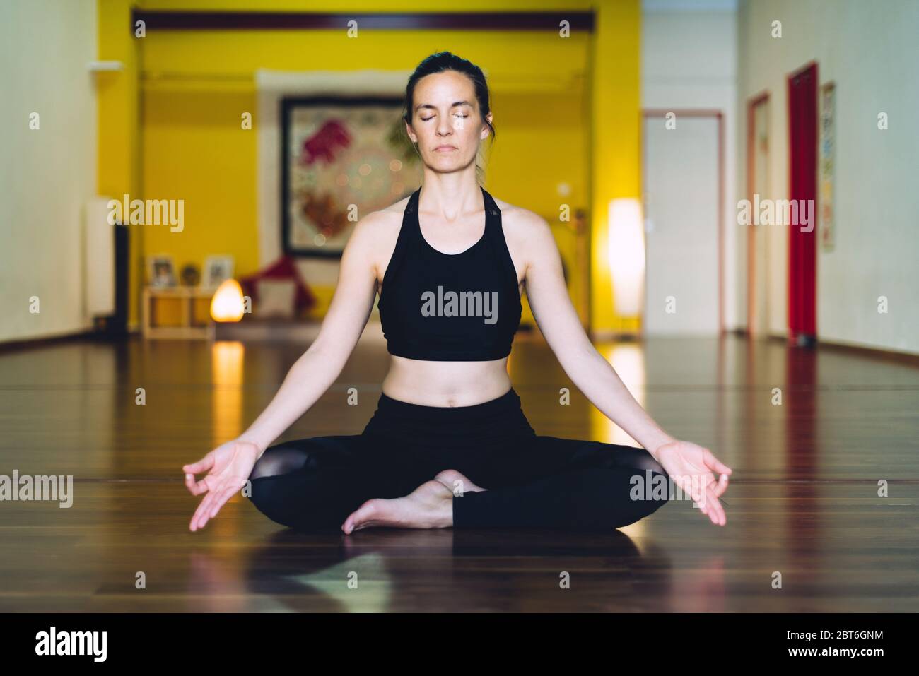 Junge Frau, die Yoga in der Meditationsposition von Sukhasana macht. Konzept der Entspannung Stockfoto