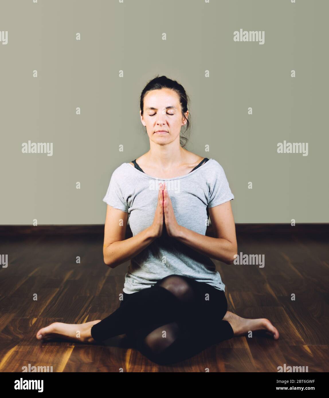Frau sitzt mit gekreuzten Beinen auf dem Boden und macht Yoga-Entspannungsübungen. Konzept des gesunden Lebens und Yoga Stockfoto