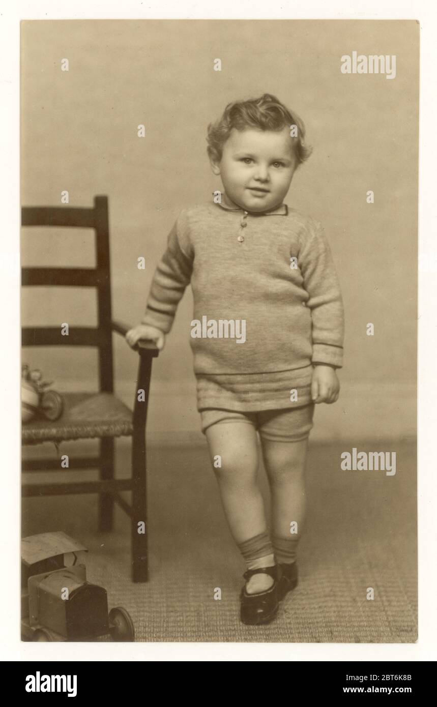 Postkarte des frühen 1900er Jahrhunderts von niedlichen kleinen Jungen Kleinkind mit lockigen Haaren, trägt einen Strickpullover und Shorts, um 1930er Jahre, Großbritannien Stockfoto