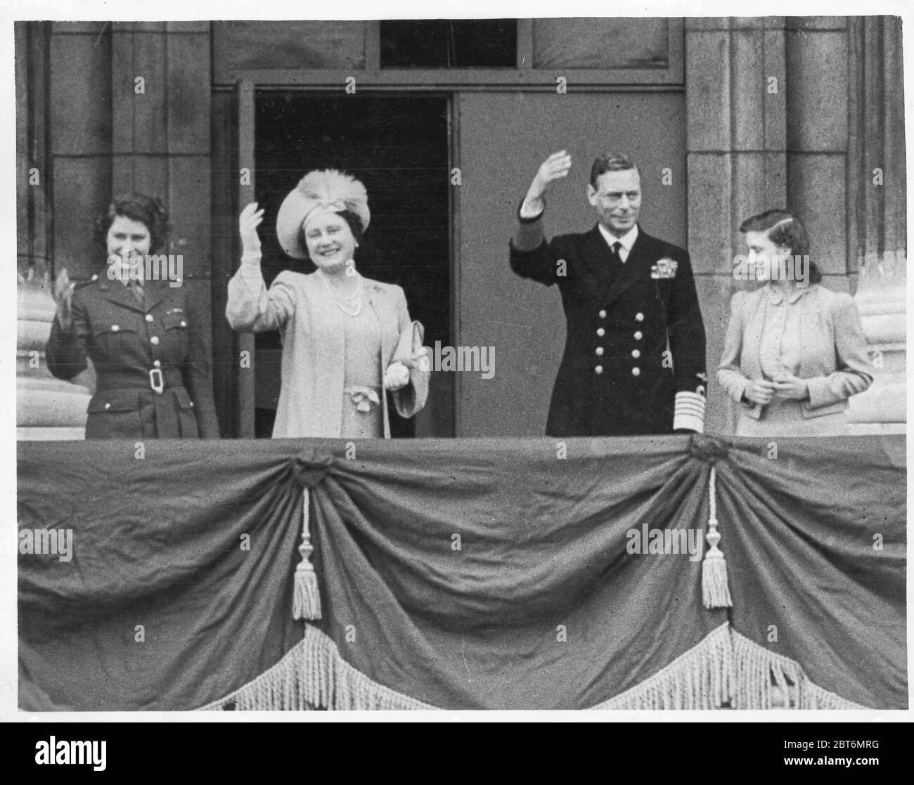 Vintage World war II Photograph - The King, George VI von Großbritannien begleitet von der Königin und den Prinzessinnen Elizabeth und Margaret auf dem Balkon des Buckingham Palace, VE Day Celebration. Stockfoto