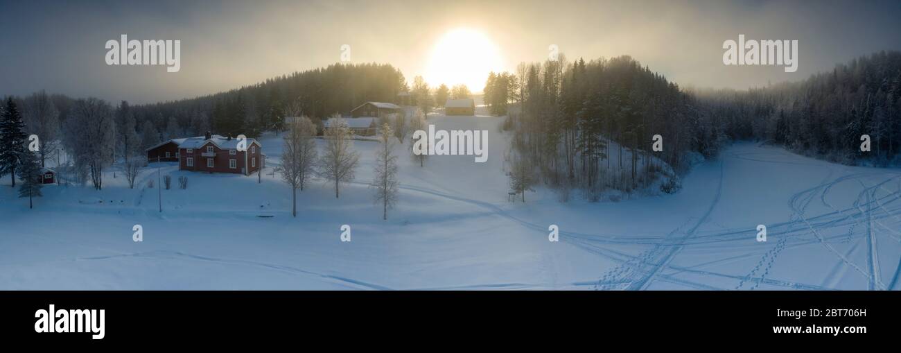 Majestätische Ansicht des Winteruntergangs mit sehr großem Sonnenfleck in gefrorener nebliger Luft, Winterkiefernwald, Luftaufnahme, Grano Dorf, um Umea Stadt, Norther Stockfoto