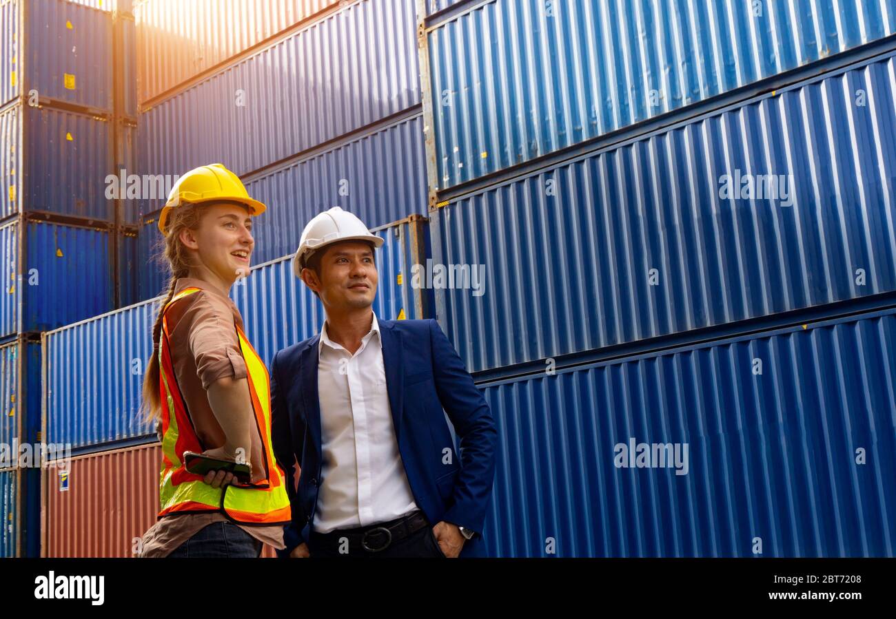 Zwei Vorarbeiter, eine Frau und ein Mann, stehen zusammen und blicken auf den Hintergrund des Frachtcontainers. Stockfoto