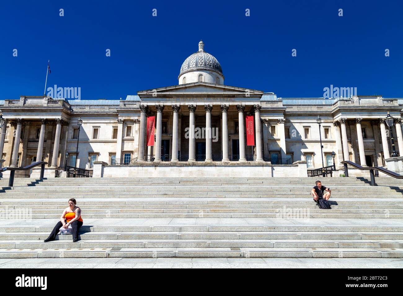 21. Mai 2020, London, Großbritannien - Menschen sitzen auf den Stufen zur Nationalgalerie auf dem fast menschenleeren Trafalgar Square während der Sperrung der Coronavirus-Pandemie Stockfoto
