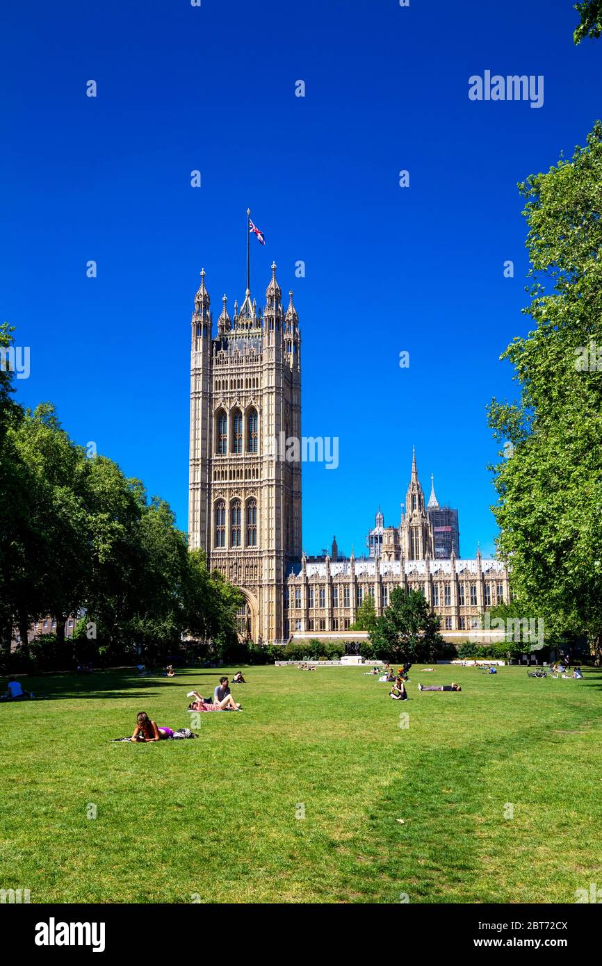 21. Mai 2020, London, Großbritannien - Menschen, die an einem heißen Frühlingstag in Victoria Tower Gardens im Südpark mit Parlamentsgebäuden im Hintergrund während des Ausbruchs der Coronavirus-Pandemie sonnenbaden Stockfoto