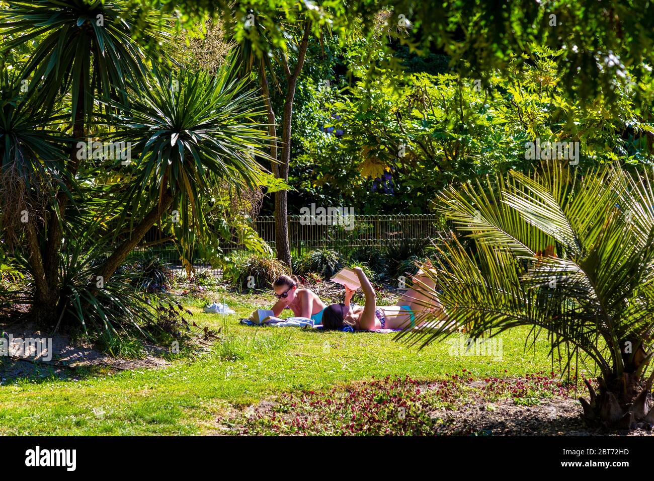 21. Mai 2020, London, Großbritannien - Menschen, die während der Sperrung der Coronavirus-Pandemie an einem heißen sonnigen Tag im Battersea Park ein Sonnenbad lesen Stockfoto