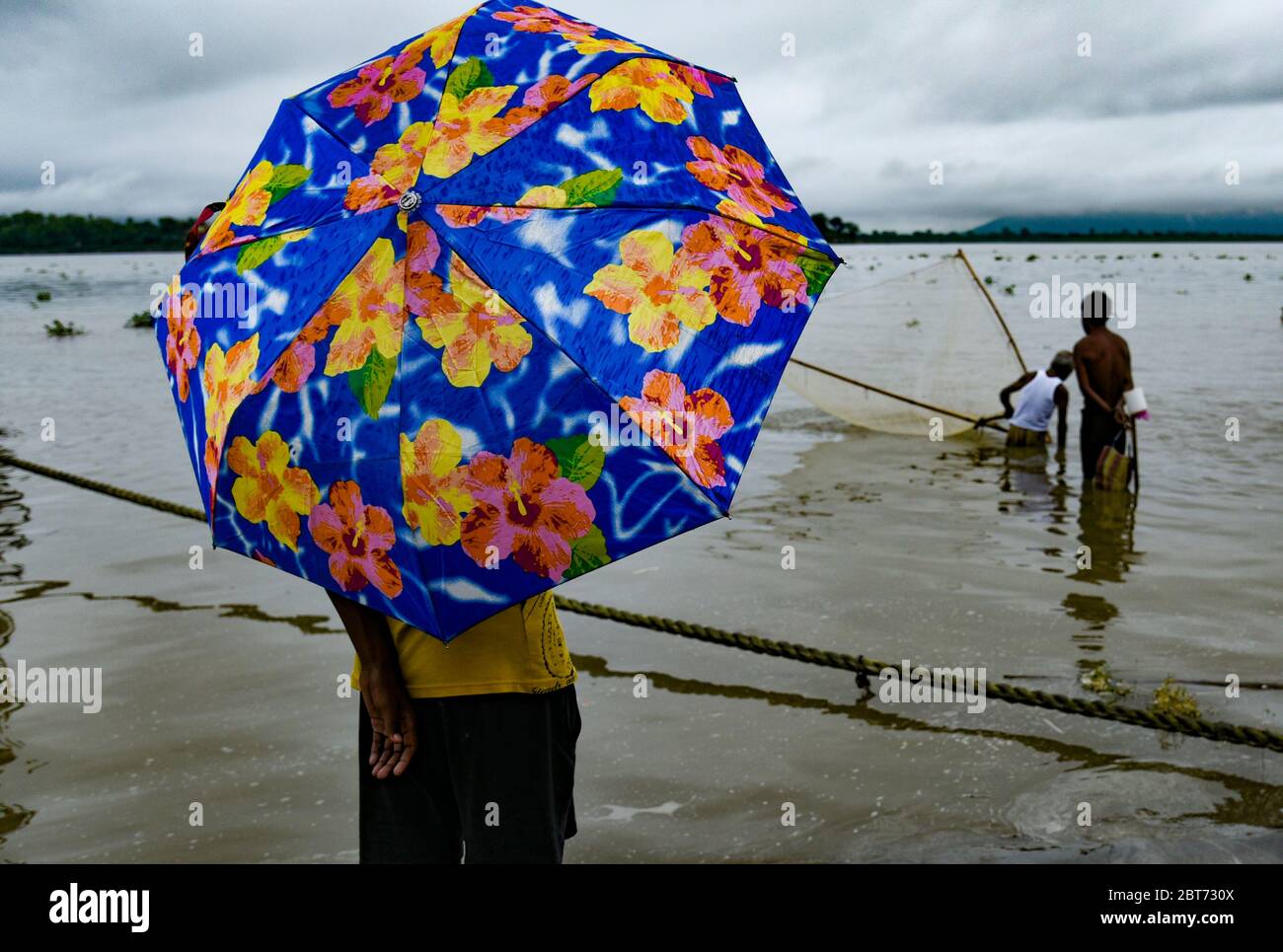 Guwahati, Assam, Indien. Mai 2020. Ein Junge unter einem Schirm am Ufer des Brahmaputra Flusses im Hintergrund von dunklen Wolken, die den Himmel während eines regnerischen Tages in Guwahati bedecken. Kredit: David Talukdar/ZUMA Wire/Alamy Live News Stockfoto