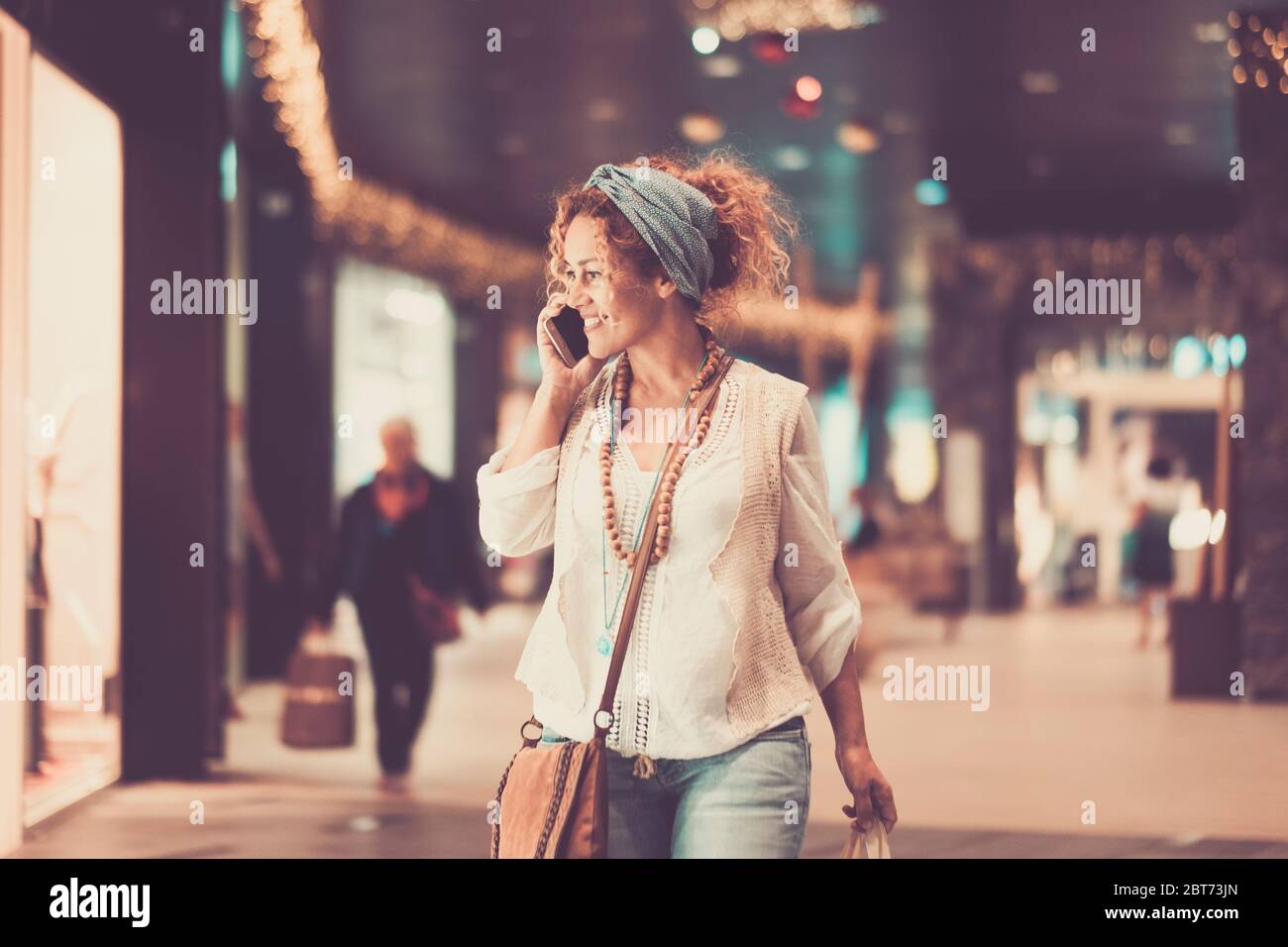 Fröhlich trendy adul kaukasischen Frau einen Anruf zu tun, während in einem Einkaufszentrum auf der Suche nach Kleidung und Kleidung zu kaufen - Shopping Freizeit Stockfoto