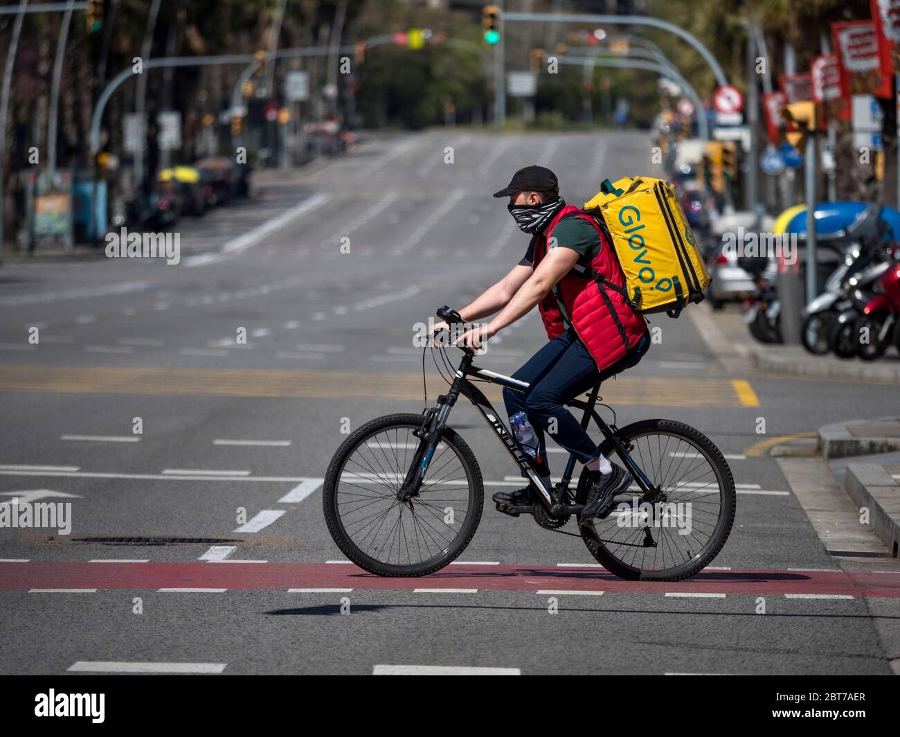 Ein Mann, der Lebensmittel liefert, fährt während des Alarmzustands wegen einer Coronavirus-Pandemie eine Straße in Barcelona mit dem Fahrrad entlang. Katalonien (Spanien), Europa Stockfoto