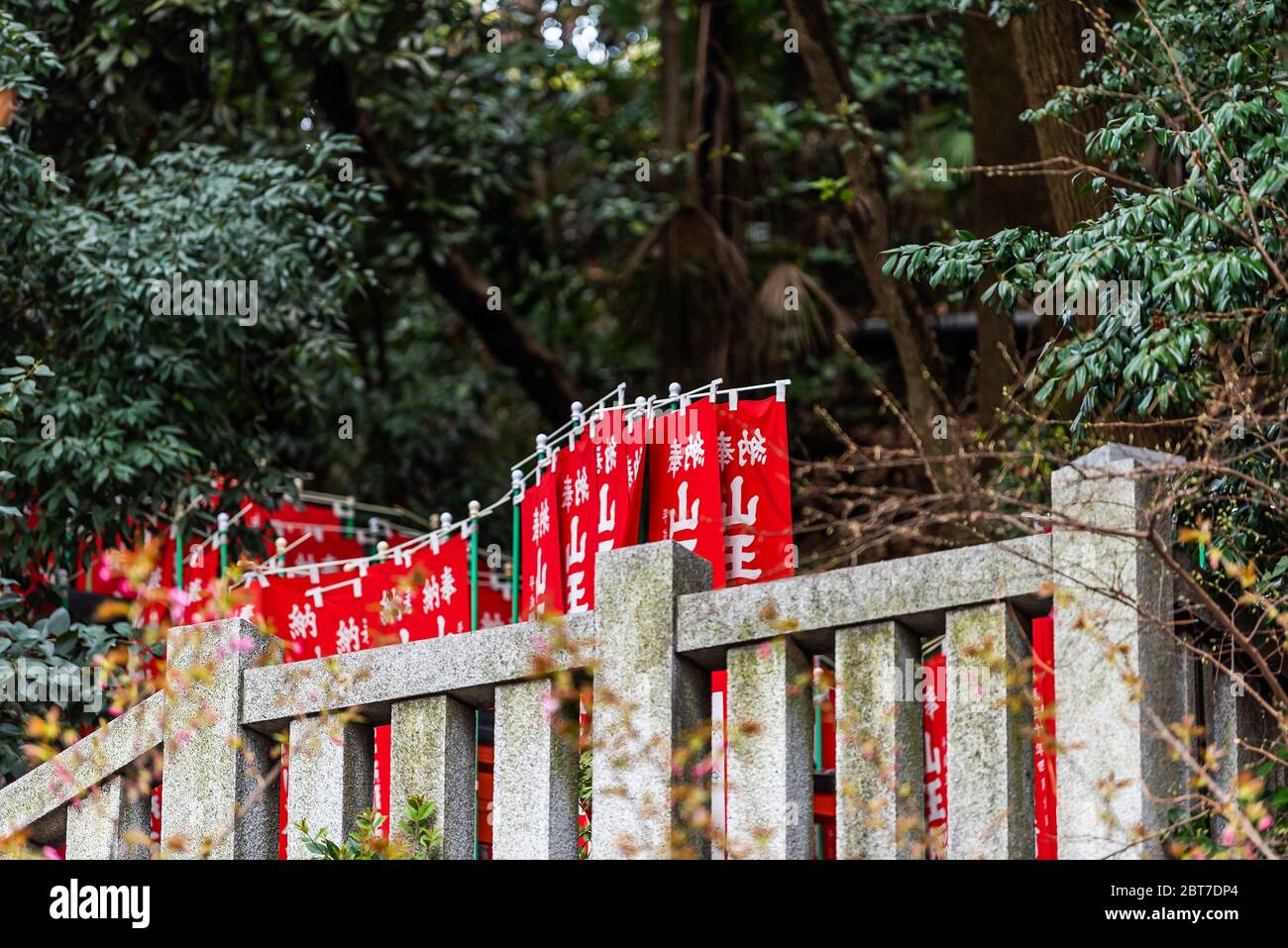Tokio, Japan - 31. März 2019: Rote Fahnen Banner genannt Nobori am Eingang des Hie Schreines in Akasaka Bezirk Bezirk Bezirk Bezirk Bezirk Bezirk Bezirk Bereich mit Pfad Treppen im Wald Stockfoto