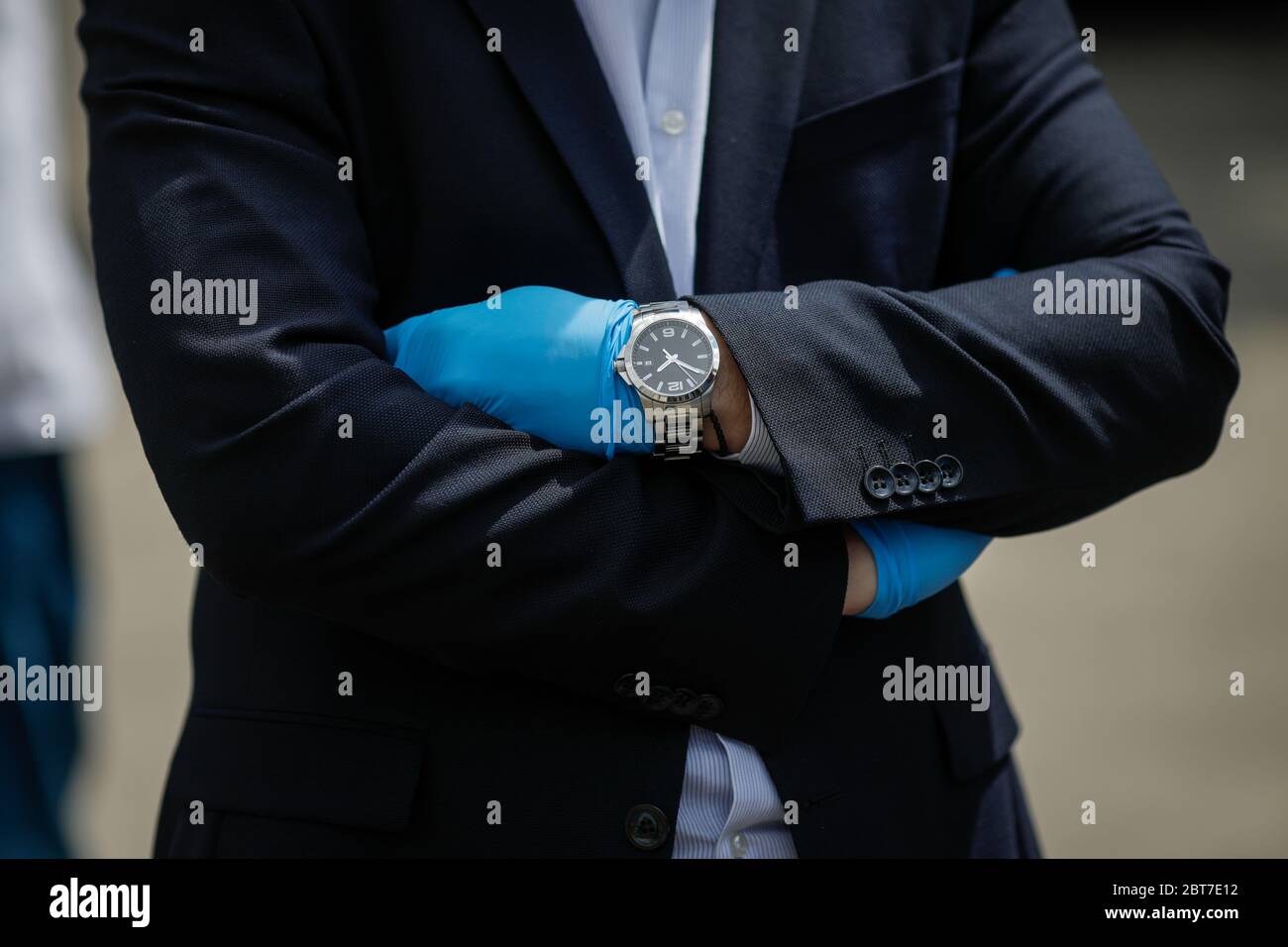 Artikeldetails mit den Händen in Handschuhen und Uhr eines wohlhabenden Geschäftsmannes während des Ausbruchs der Covid-19. Stockfoto