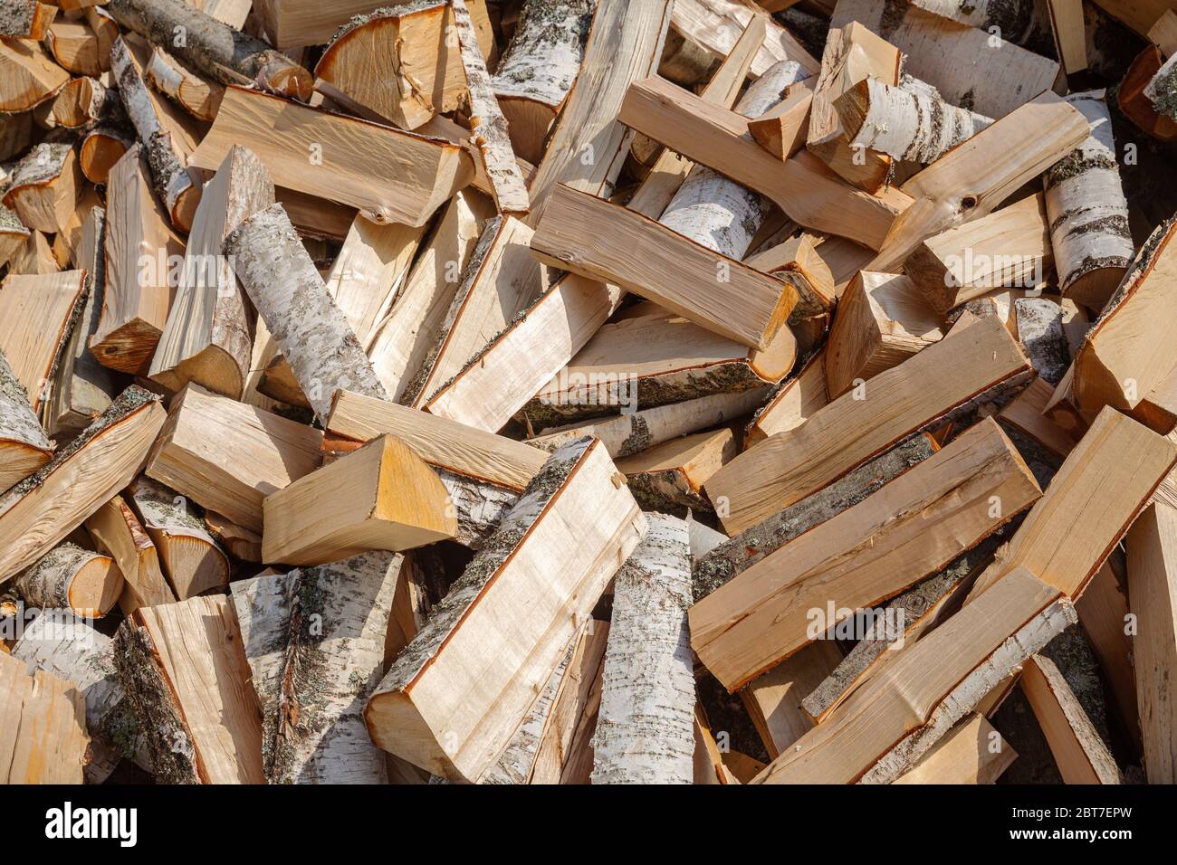 Hintergrund von gehacktem Brennholz. Holzlager für die Ofenheizung für den Winter. Abgebropfte Birkenstämme in einem großen Haufen Stockfoto