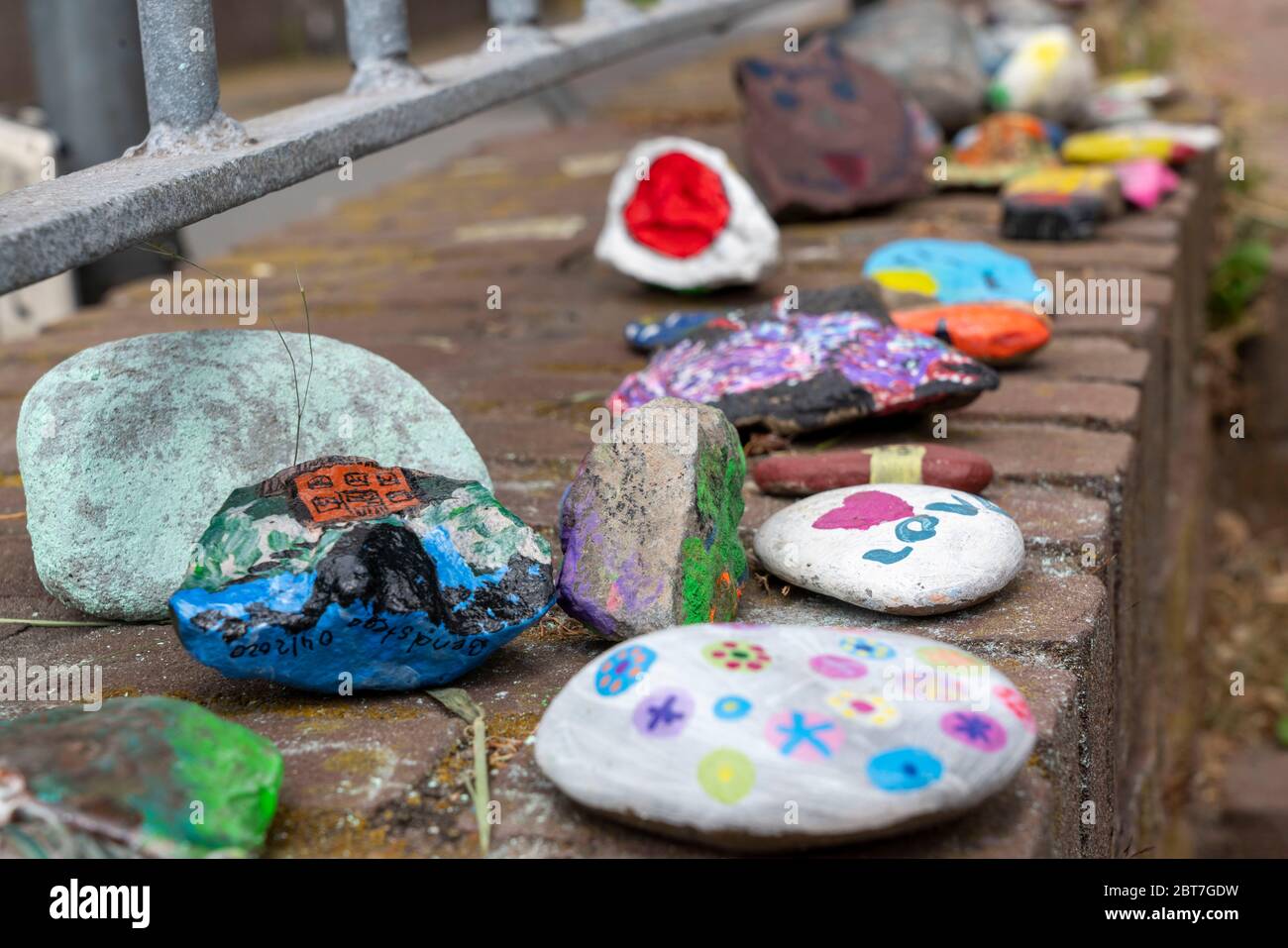 Bemalte Steine an einer Wand in Duisburg-Orsoy, sogenannte Corona-Steine, Steinschlangen, die meist Kinder malen und zu einer Reihe zusammenfügen, wirken wieder Stockfoto