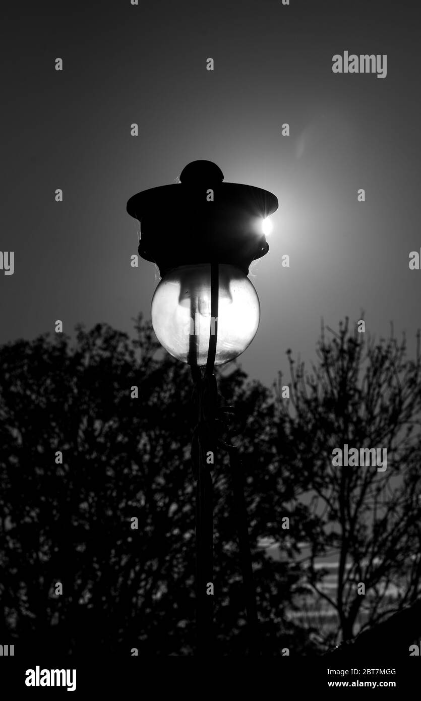 Alte Straßenlaterne auf dem Mound beleuchtet durch das Sonnenlicht von der Waverley Station Edinburgh. Dramatische Schwarzweiß-Aufnahme. Stockfoto