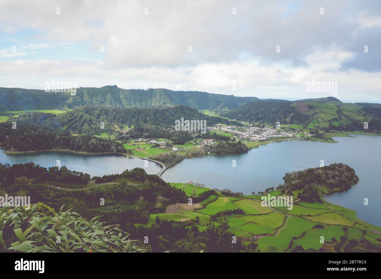 Herrlicher Blick auf die Lagoa Azul und das Dorf Sete Cidades vom Aussichtspunkt Miradouro do Cerrado das Freiras in Azoren, Portugal. Seen umgeben von grünen Feldern und Wald. Horizontales Foto. Stockfoto
