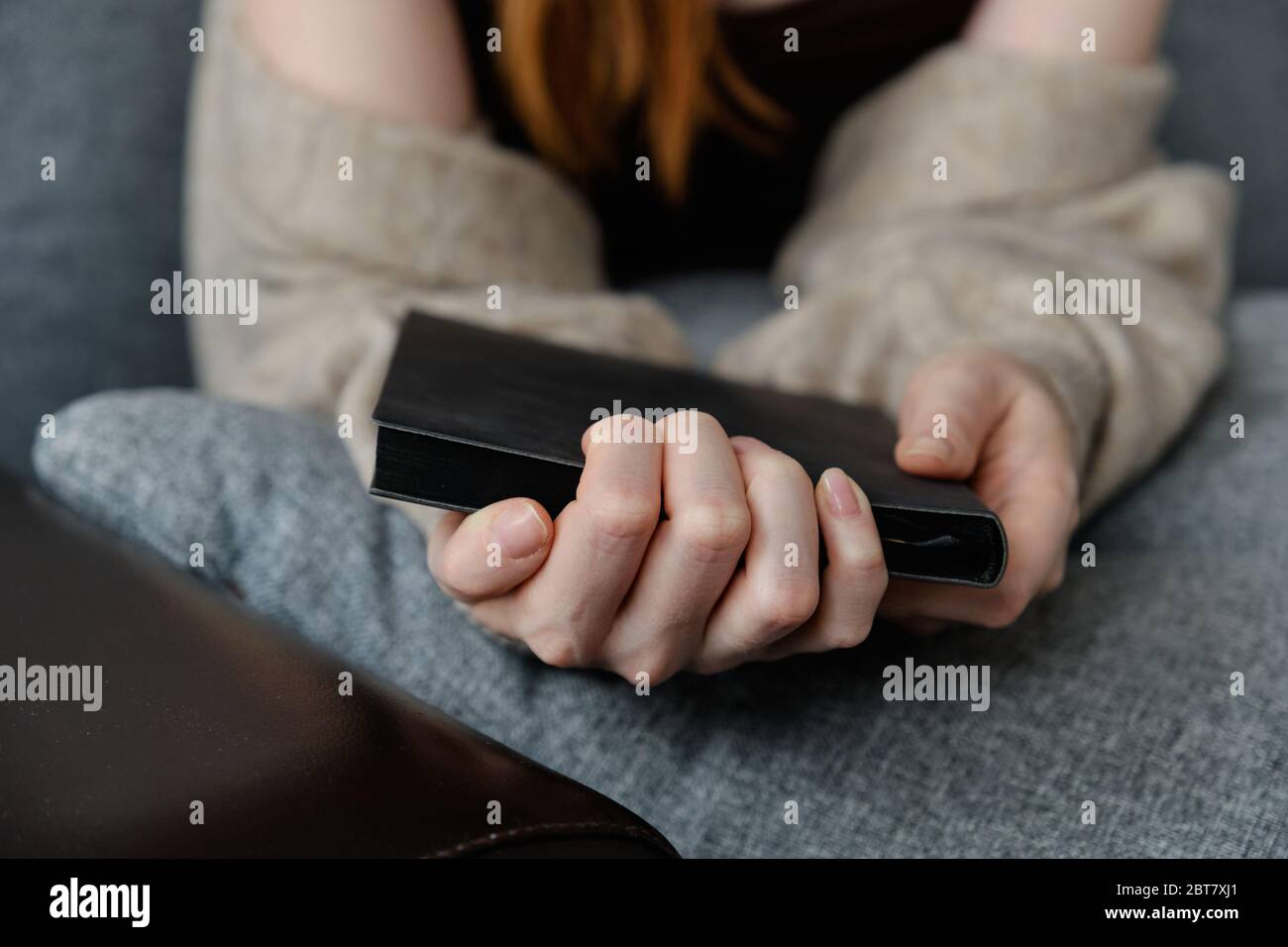 Foto von Frauenhände mit einem schwarzen Buch schließen, Finger im Fokus. Stockfoto