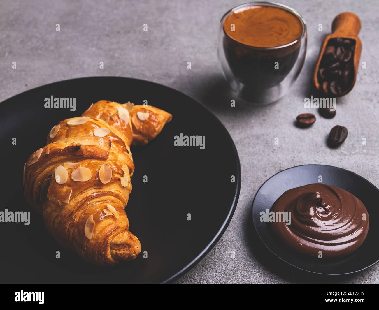 Leckere frische Croissants in Scheiben geschnittene Mandeln mit Kaffee und Schokoladenpaste auf dem Teller Stockfoto