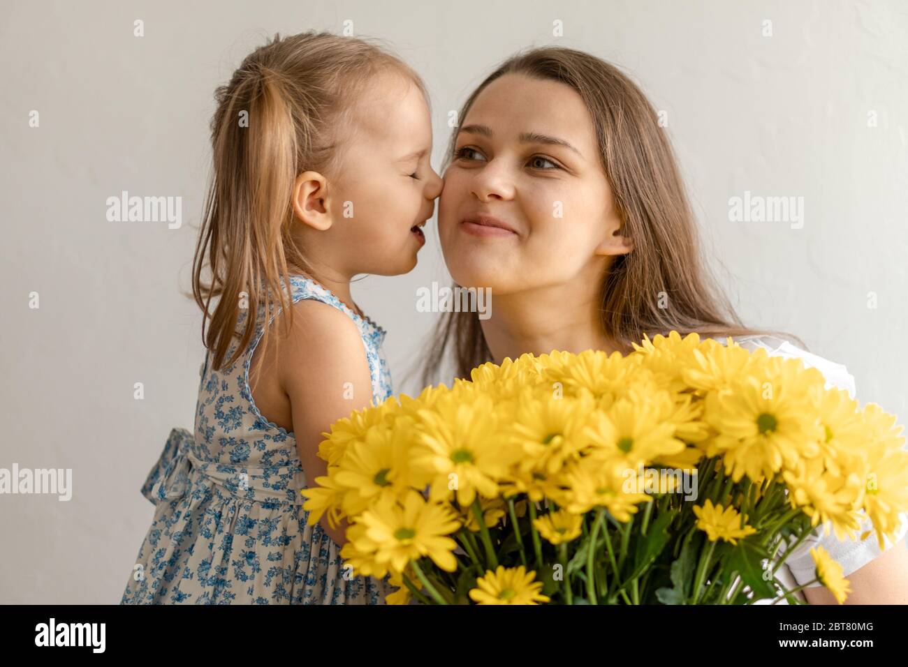 Mutterschaft, Muttertag, Geburtstag, Kindheit, Familienkonzept - close-up kleines Mädchen in der Kleidung gratulieren und geben junge Mutter Bouquet von gelb Stockfoto